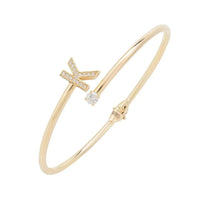 Gold-tone bangle bracelet with crystal cross charm and small square stone accents
