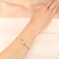 Gold tone N initial bangle on wrist, thin hinged cuff with crystal details