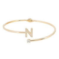 Gold tone hinged bangle with N initial and crystal accents in openwork design