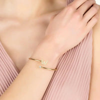 Gold W initial bangle worn on wrist, with small crystal W and stones