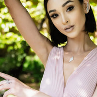 Silver angel wing pendant necklace worn on a model’s neckline with delicate chain