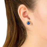 Gold lapis lazuli round stud earrings on ear, blue gemstone disc