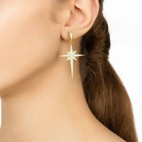 Gold star drop earrings with sparkling starburst and long pointed drop on ear