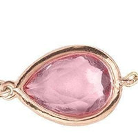 Close-up rose-gold teardrop bracelet with pink gemstone bezel