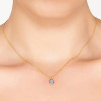 Gold teardrop pendant necklace with blue stone, worn at collar