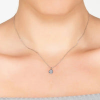 Silver teardrop pendant necklace with light blue topaz worn at the neckline