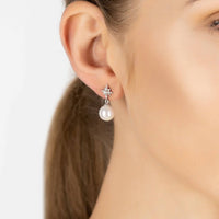 Silver star and pearl drop earrings on model ear, side view