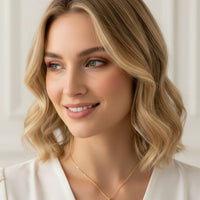 Gold round pendant necklace with blue stone on a model’s neckline