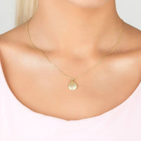 Gold shell pendant necklace with thin chain worn at the collarbone