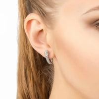 Silver snake huggie hoop earrings on ear with green enamel and clear stones