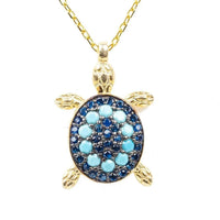 Gold-tone pendant necklace with blue turtle charm and turquoise bead accents
