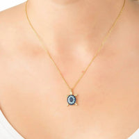 Gold-tone pendant necklace worn at neckline, blue turtle charm with turquoise stones