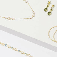 Gold-tone jewelry set with chain necklace and small green gemstone earrings