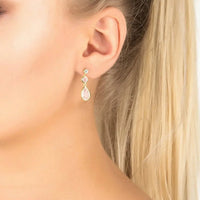 Gold-tone drop earrings with pale pink teardrop gemstone on ear