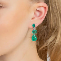 Silver drop earrings with green teardrop and square stones, seen on a hook ear back