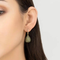 Gold teardrop dangle earrings with textured green gemstone drops, worn on ear