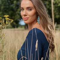 Turquoise teardrop earrings with long silver cascade, worn with blue top
