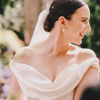 Silver flower-and-pearl stud earrings on a bride’s ear