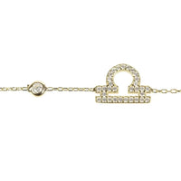 Gold tone bracelet close-up with CZ zodiac pendant and small round charm