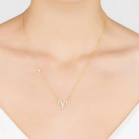Gold Aries zodiac pendant necklace on model neckline, small rhinestone charm
