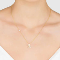 Gold zodiac pendant necklace with small Capricorn charm, worn