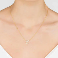 Gold-tone zodiac pendant necklace on model, Taurus symbol with stone border