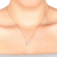 Rose gold Virgo zodiac pendant necklace on neckline with thin chain and small bead links.