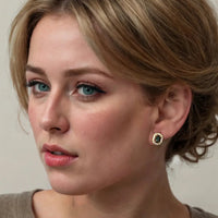 Gold emerald-green gemstone stud earrings with clear halo on ear