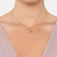 Gold pendant necklace with small peridot-green gemstone on a fine chain