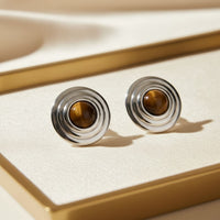 Silver tiger's eye stud earrings with concentric ring design, shown on display