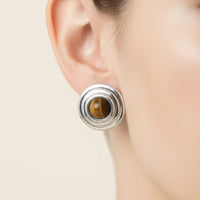 Silver stud earrings with stacked circles and brown tiger's eye center, on ear