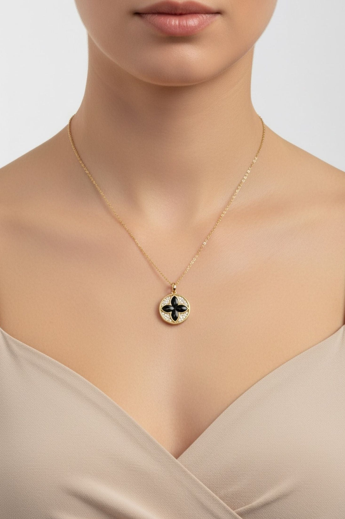 Gold clover pendant necklace on a thin chain, black enamel charm at collarbone