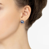 Blue sapphire stud earrings on ear with silver setting and crystal border