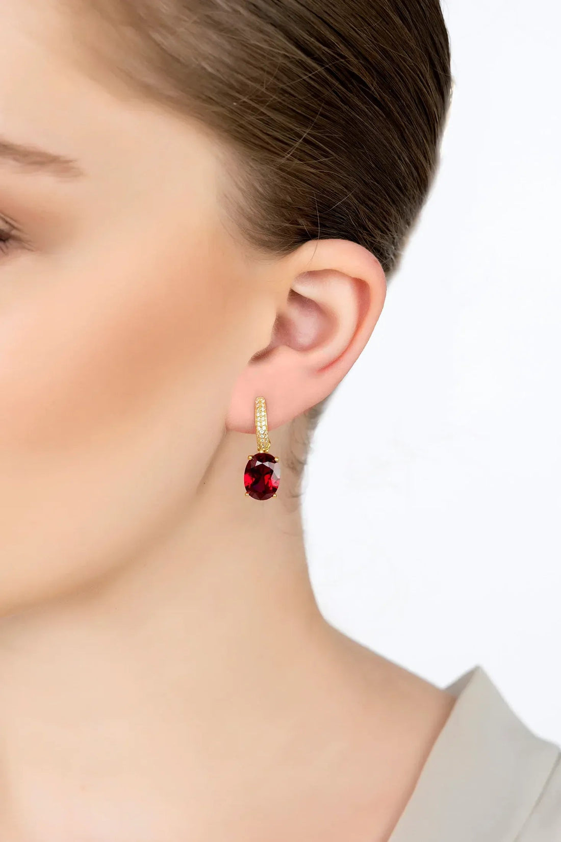 Gold hoop-style drop earrings with oval dark red gemstone and crystal accents