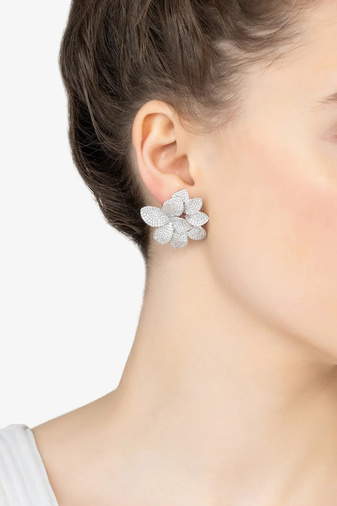 Silver textured flower stud earrings on ear, five layered petals