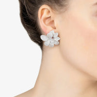 Silver textured flower stud earrings on ear, five layered petals