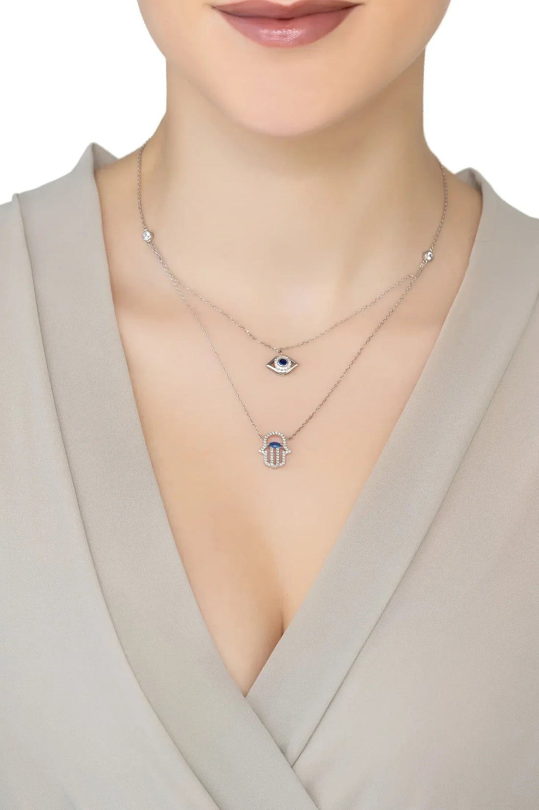 Silver layered charm necklace on model: evil eye and hamsa with two chains