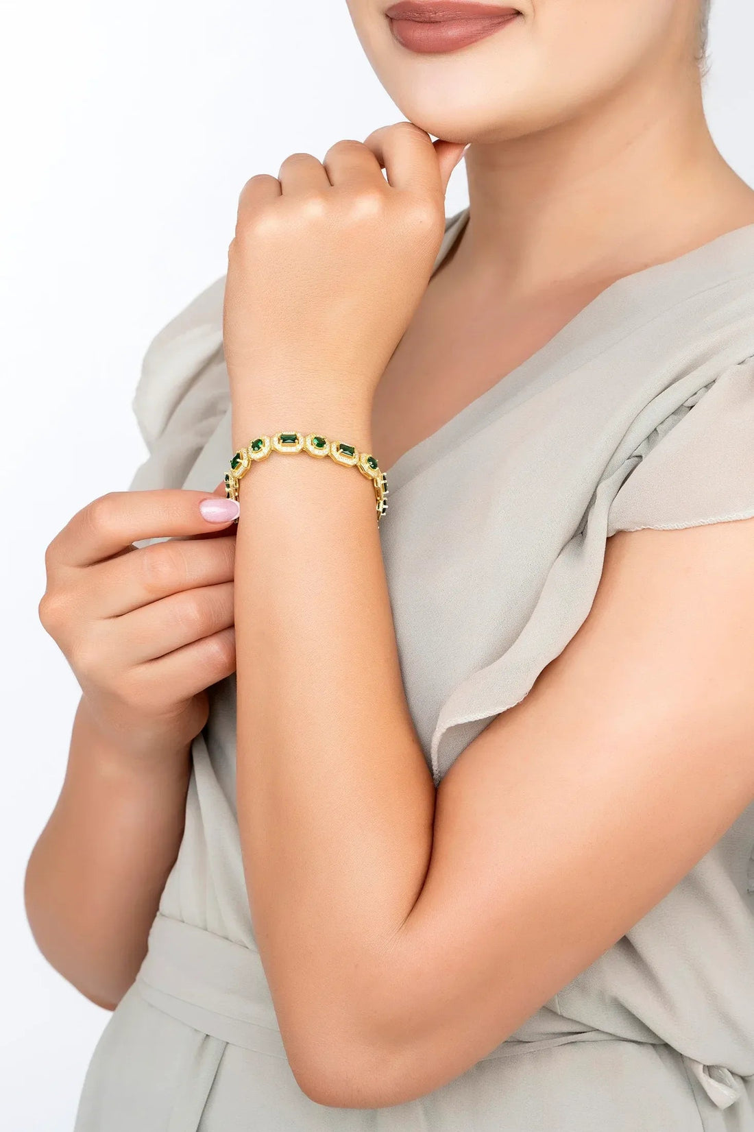 Gold-tone emerald gemstone bracelet on wrist with green stone link accents