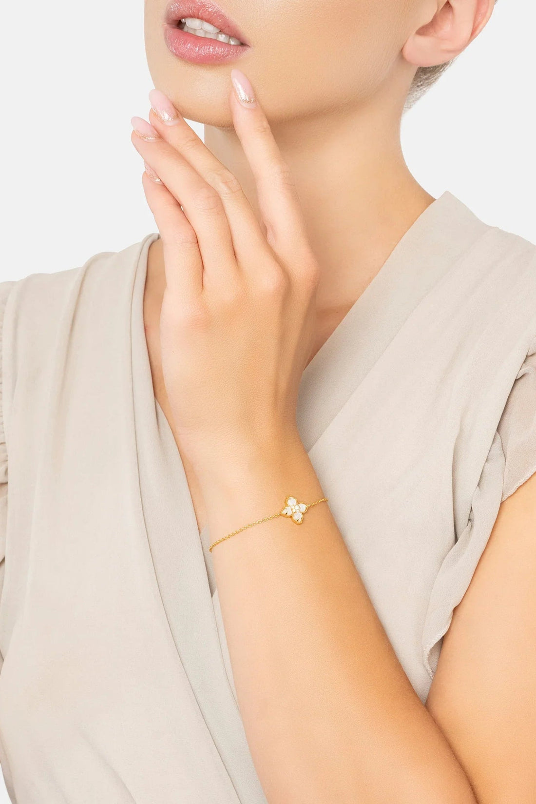 Gold bracelet with mother-of-pearl flower clover charm on wrist