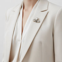Bee brooch on light blazer lapel, faux pearl center with rhinestone wings