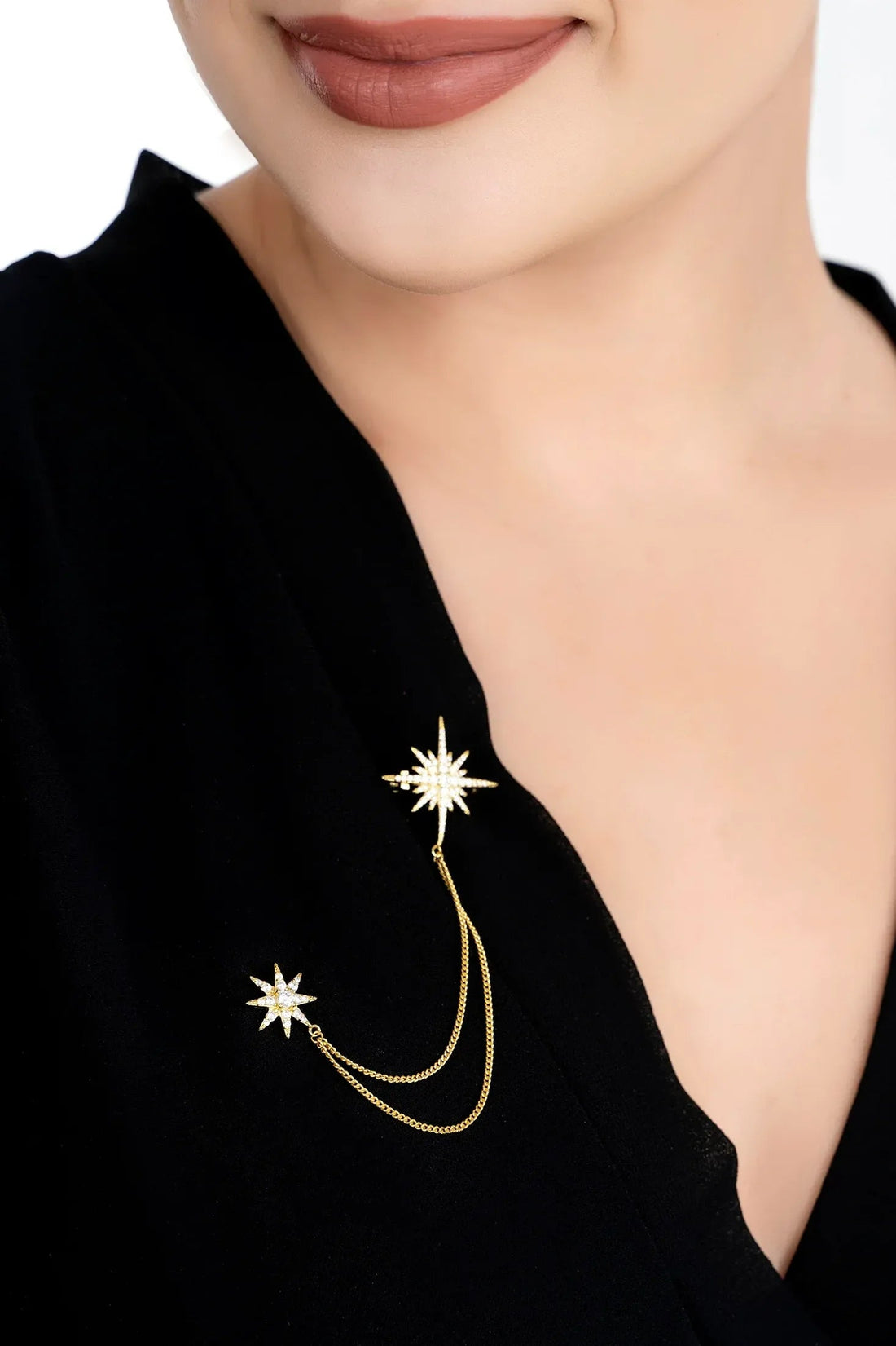 Gold starburst brooch with pin, dangling chains and star accents