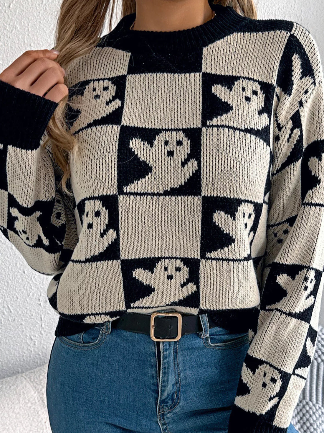 Black and cream checkerboard knit Halloween sweater with ghost face graphics, long sleeves