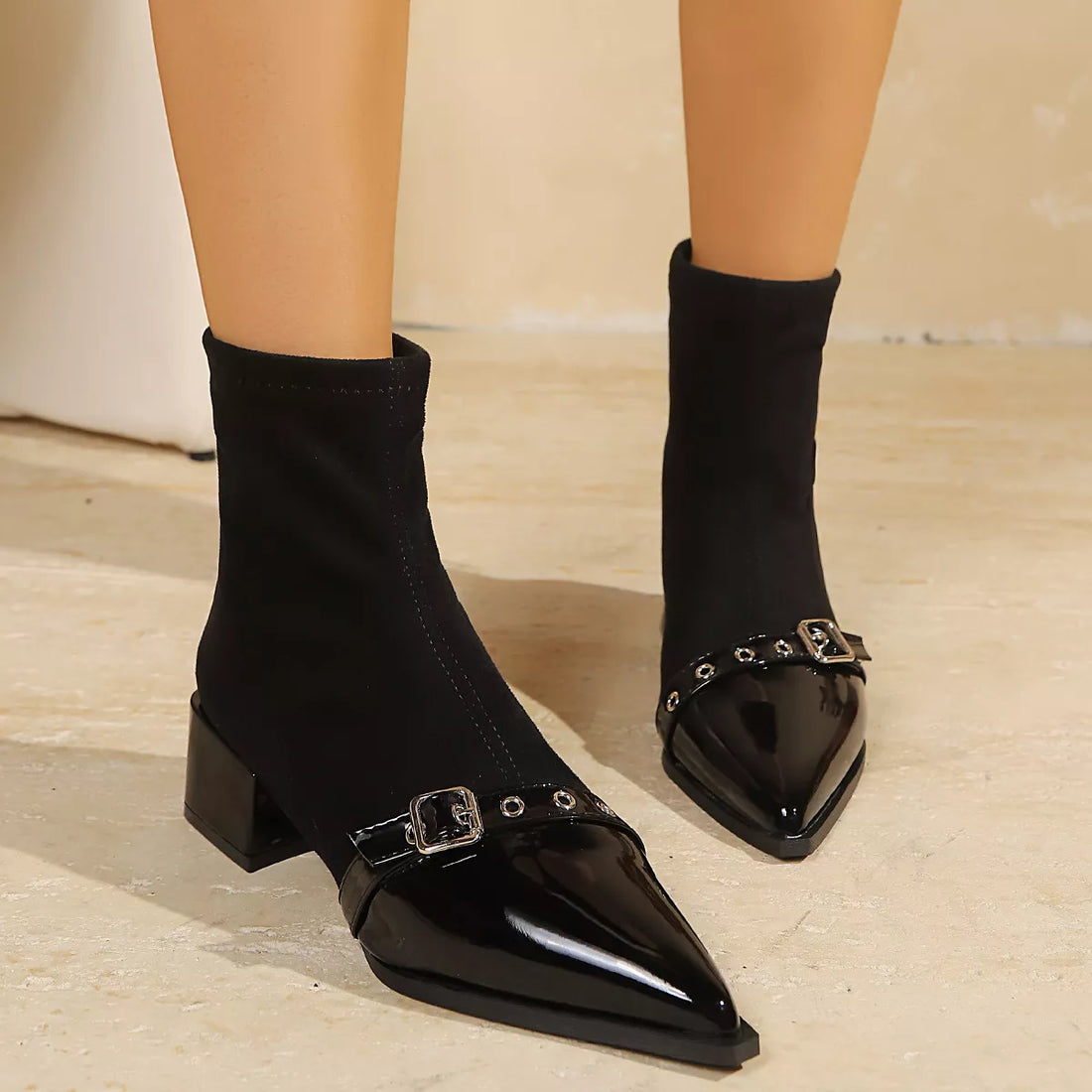 Black sock boots with pointed toe, buckle detail, and block heel