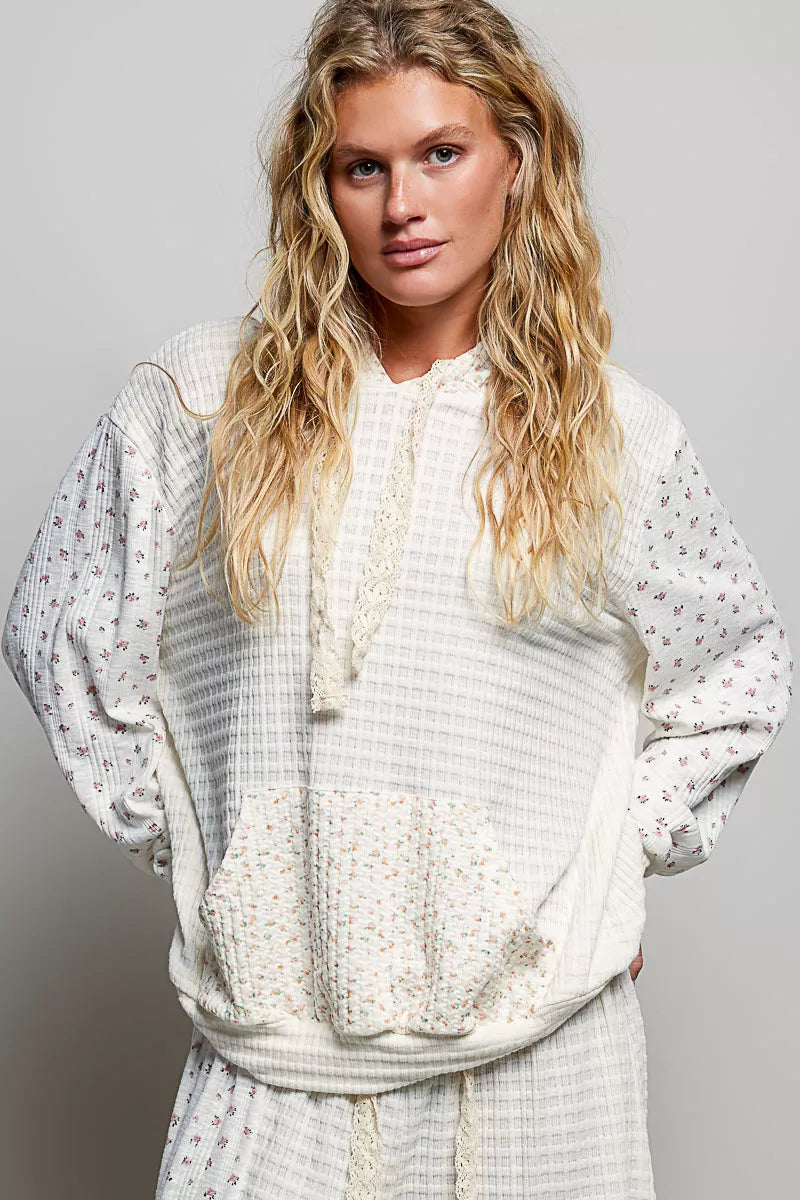 Cream knit hoodie with floral print sleeves, hood strings, and kangaroo pocket