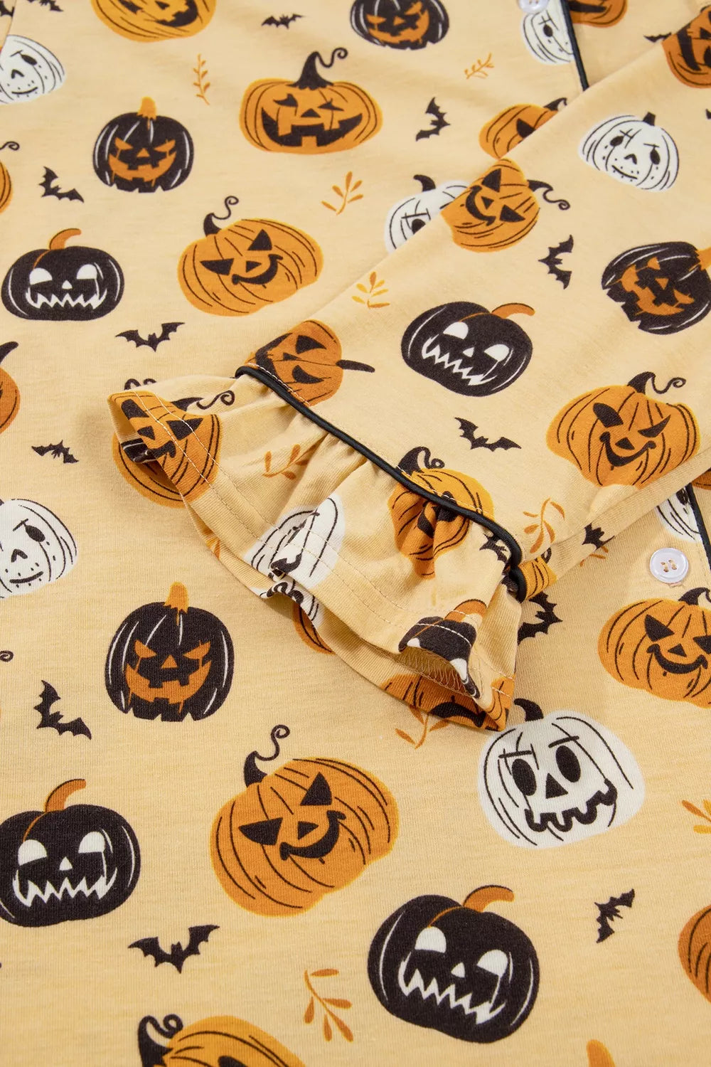 Gold Halloween pumpkin print shorts close-up, elastic waistband and ruffled trim
