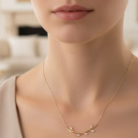 14k gold blooming branch necklace close-up at neckline, delicate leaf pendant