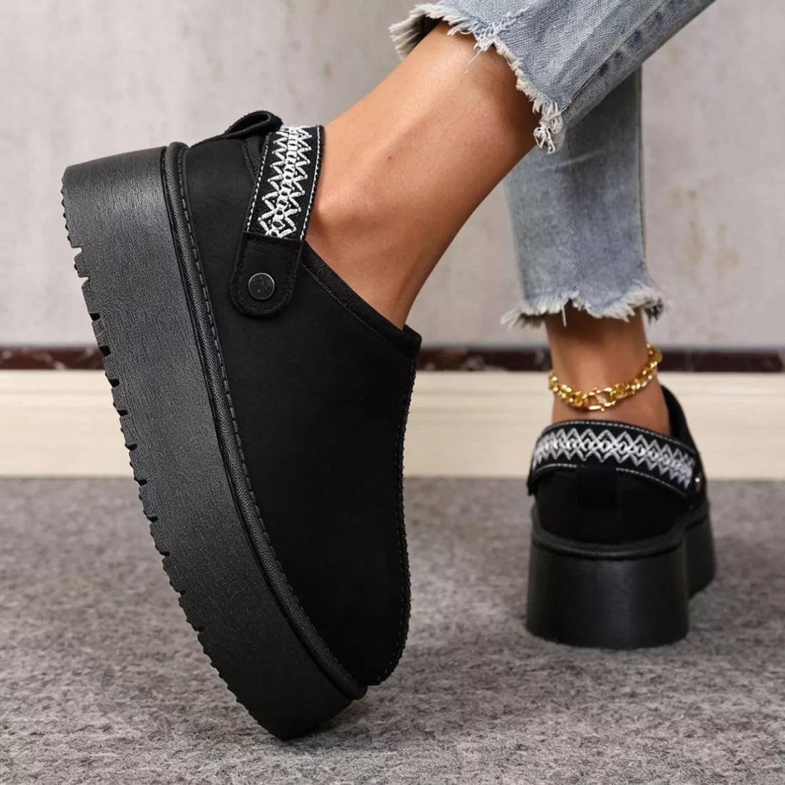 Black suede fur-lined platform boots with embroidered strap detail and thick sole.