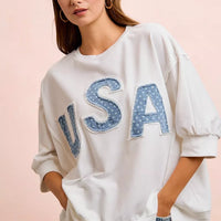 Ivory french terry sweatshirt with blue "USA" appliqued letters and loose elbow-length sleeves
