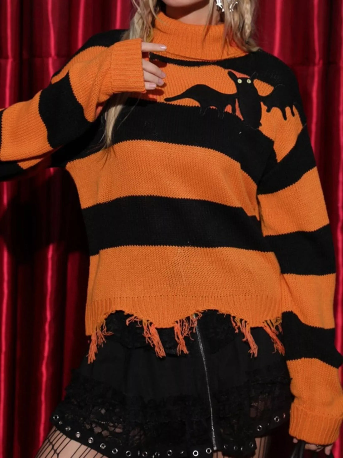 Orange and black striped turtleneck sweater with bat graphic, uneven raw hem