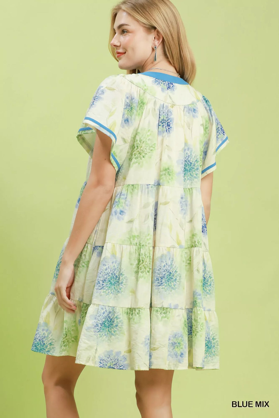 Floral babydoll dress back view with blue contrast trim and tiered skirt on cream